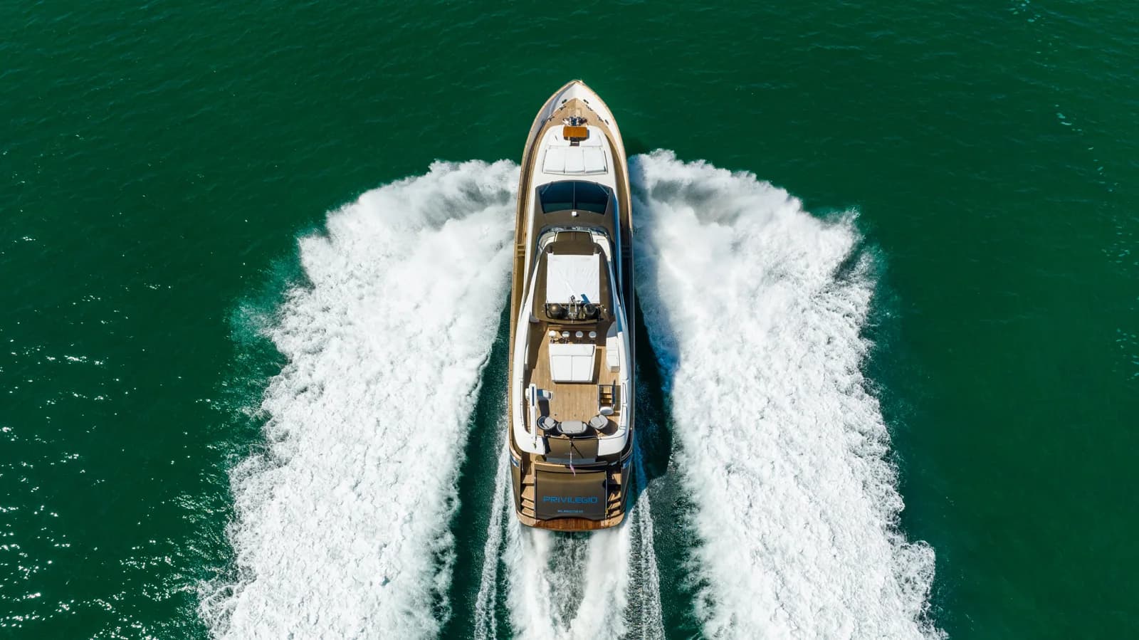 An overhead view of a private yacht making its way through emerald water